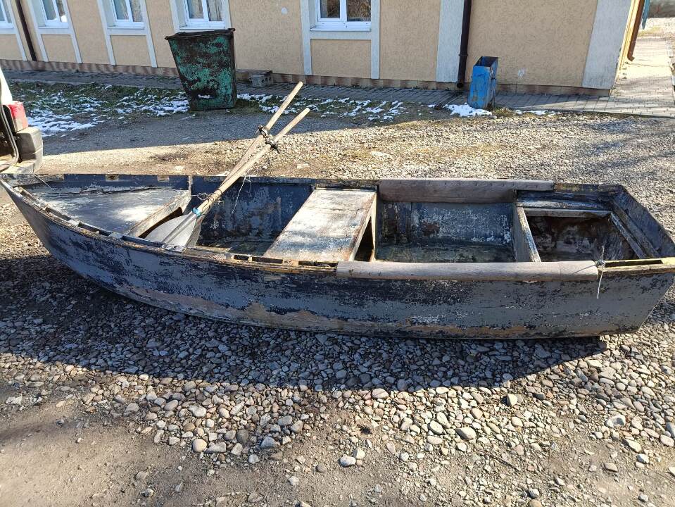 Пластиковий човен сірого кольору з двома веслами, бувший у використанні ...