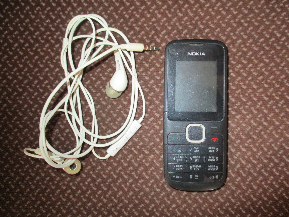 Мобільний телефон марки NOKIA C1, чорного кольору, б/в та навушники білого кольору б/в