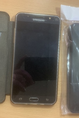 Мобільний телефон марки Samsung "Galaxy J7", чорного кольору, б/в та два чохли чорного кольору, новий та б/в