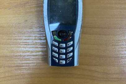 Мобільний телефон торгової марки «Telit» сірого кольору з батареєю живлення