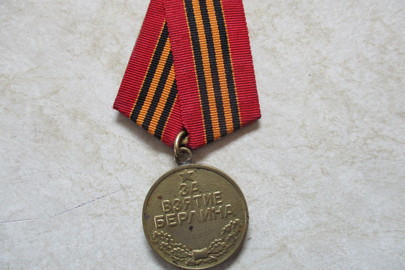 Медаль з металу жовтого кольору, на передній поверхні якої є зображення п’ятикутної зірки з надписом «За взятие Берлина», зі зворотнього боку надпис «2 мая 1945»