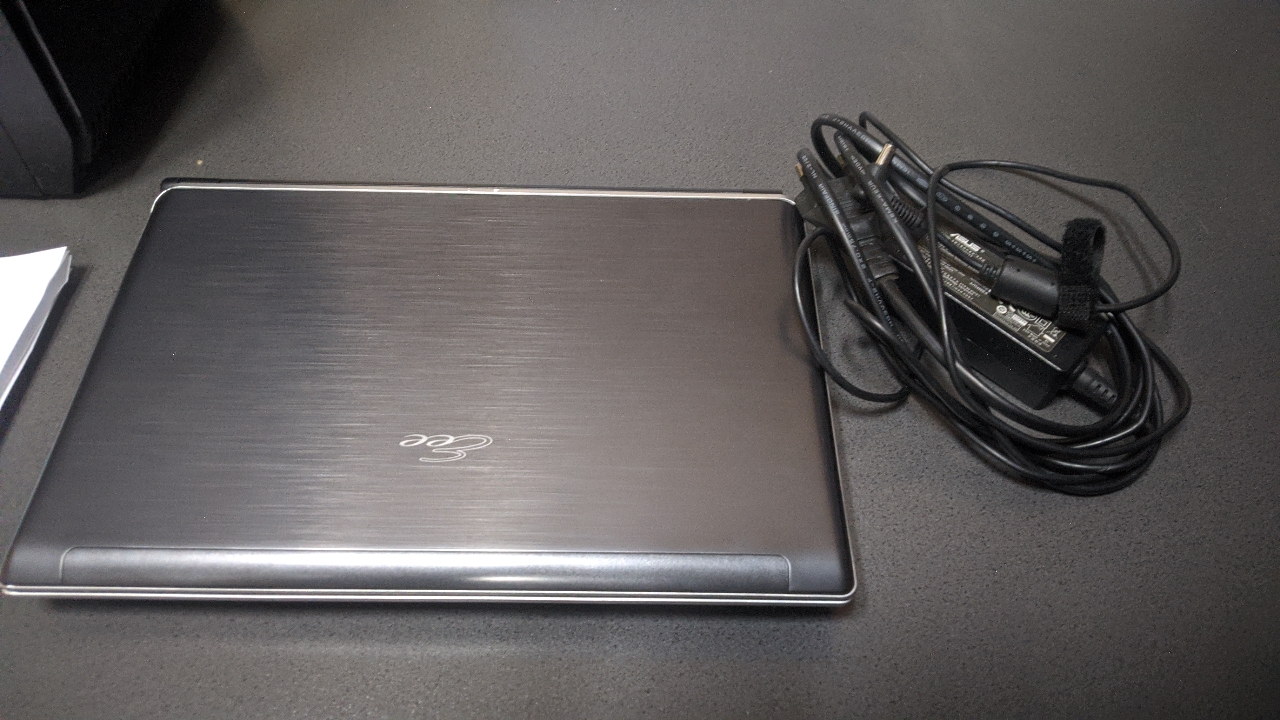 Ноутбук ASUS 950AAS086839 у корпусі чорного кольору та блок живлення до нього