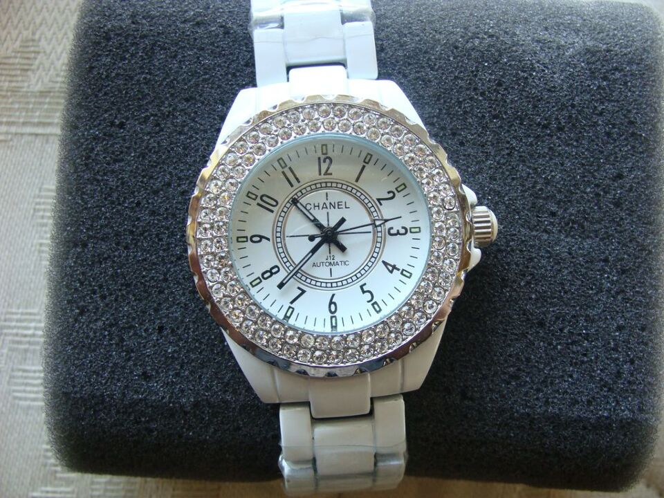 Годинник жіночий з механічною індикацією, з написом на білому циферблаті «Chanel», вироблений з металу білого кольору, з розсипами камінців білого кольору по колу корпусу