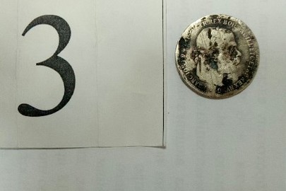 Монета з металу темно сріблястого кольору, аверс-малюнок  з гілками листя та нечітким роком виготовлення, реверс портрет невідомої людини, гурт гладкий